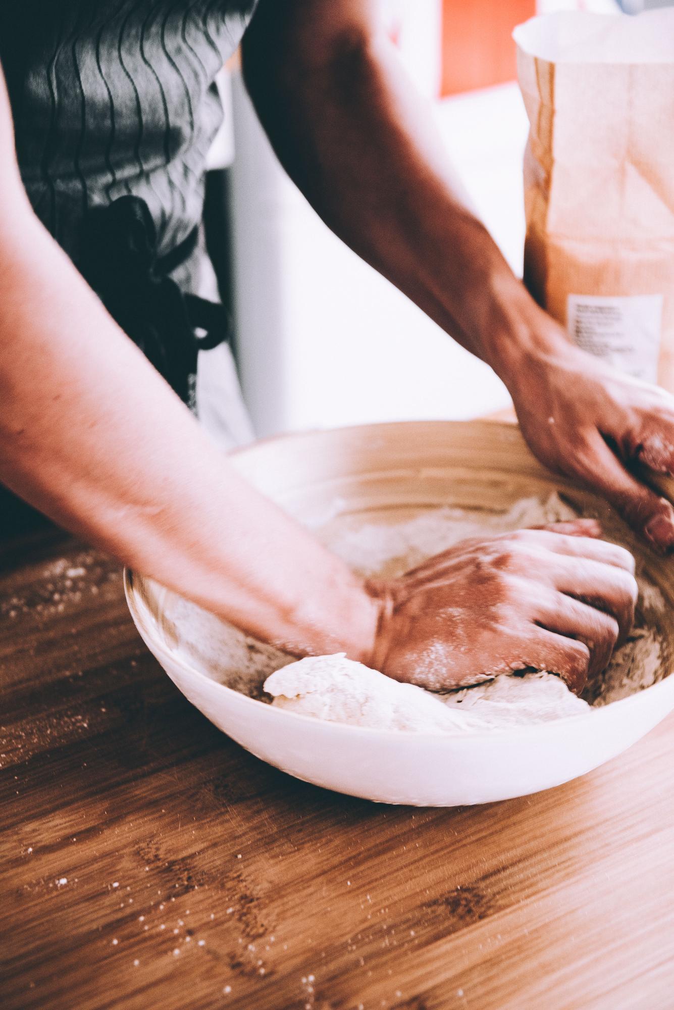 Student kneading dough on wooden table